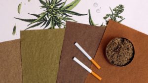 Botani Hemp filler in a paper bowl next to cigarettes wrapped in Botani Hemp paper laying on top of natural Botani Paper