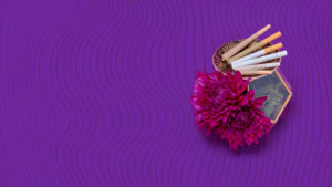 Hemp Cigarettes & pre-rolled joints displayed on a small decorative plate on top glass container holding flowers & moss over a purple background