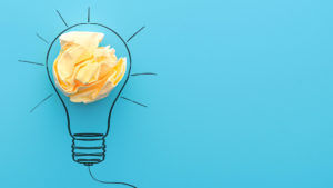 Lightbulb drawing on blue paper with a yellow crumbled paper in the bulb